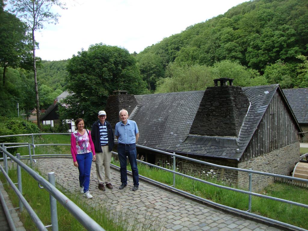 Uta, Charles, and Albert posing in front of a building powered by a massive water wheel.