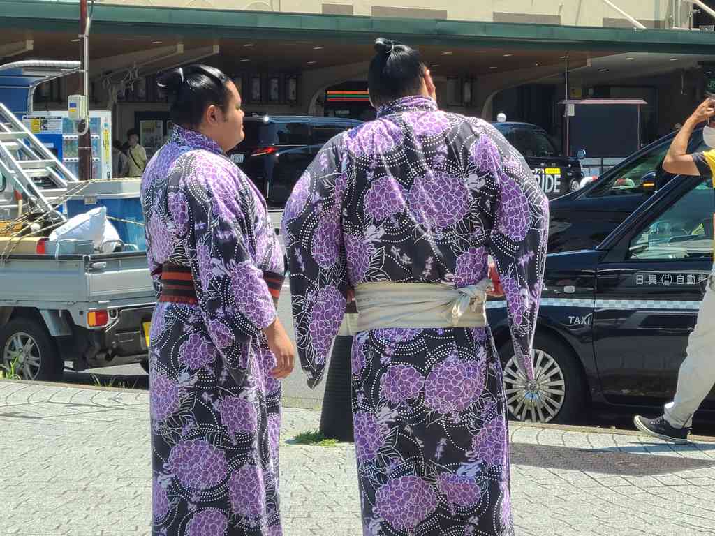 Two more massive wrestlers walking by the crowds.